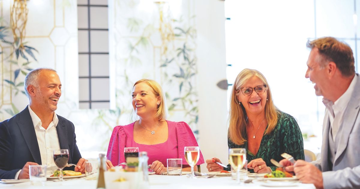 Two couples laughing and joking in the Eden Restaurant at Five Lakes, while enjoying a meal